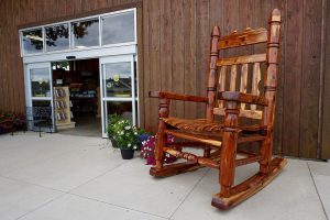 Holz Schaukelstuhl sehr Massiv der aud einer Terrasse steht neben Blumen